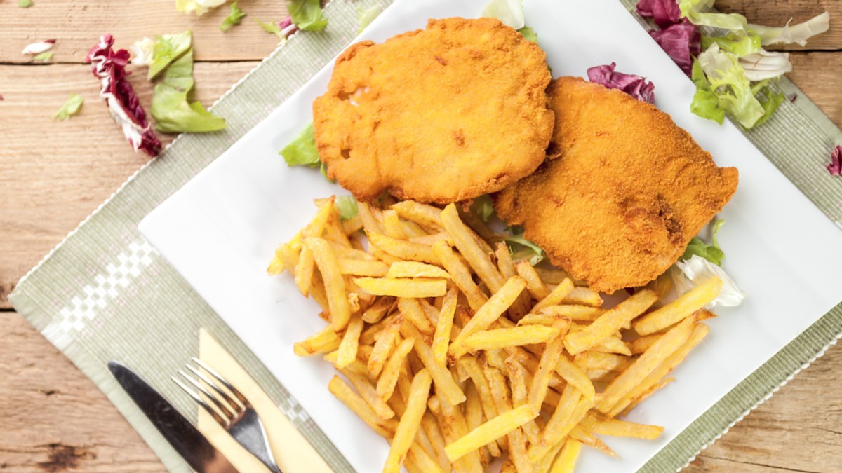 Patru reţete de carne pane - Imagine cu o farfurie pe care se află două şniţele cu cartofi prăjiţi.