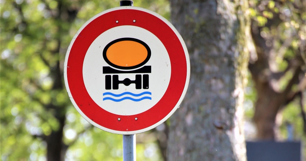 Imaginea prezintă un indicator rutier circular cu margine roșie, care interzice accesul vehiculelor ce transportă substanțe periculoase pentru mediu sau ape.