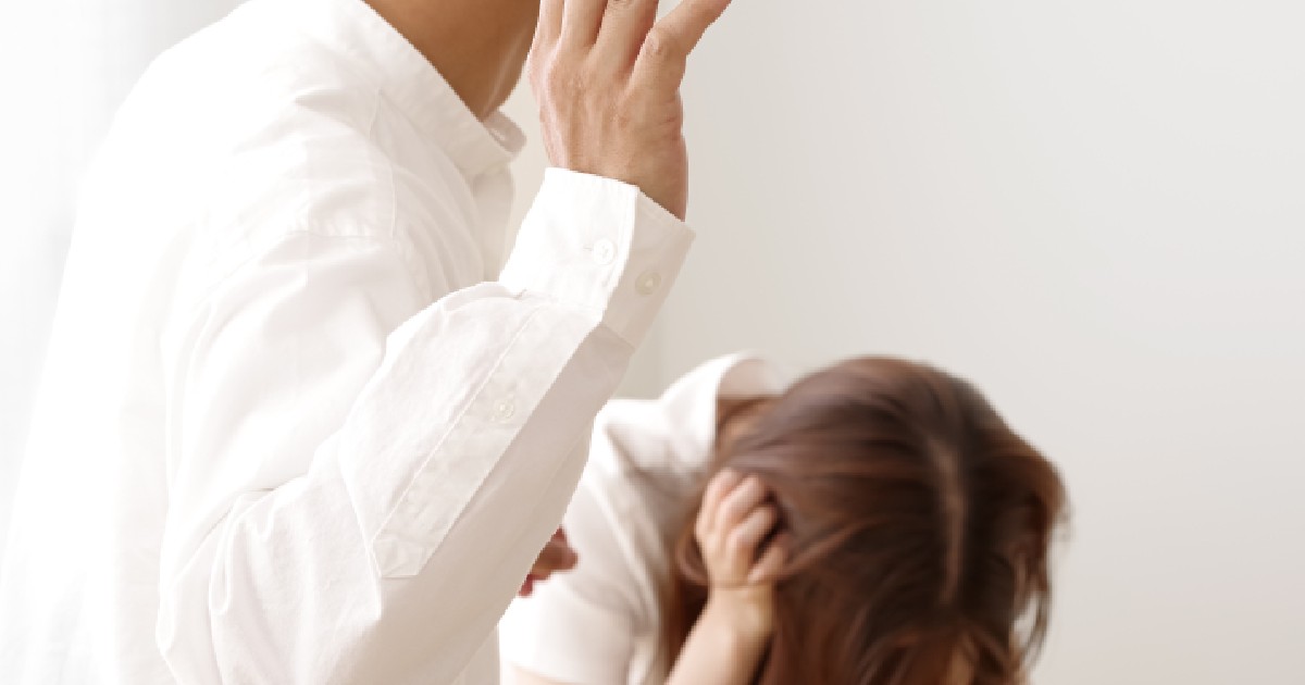 un bărbat ridică mâna să lovească o femeie care stă ghemuită și plânge