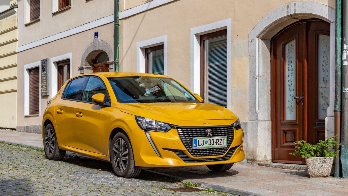 Poză cu un Peugeot 208 galben parcat în fața unei clădiri