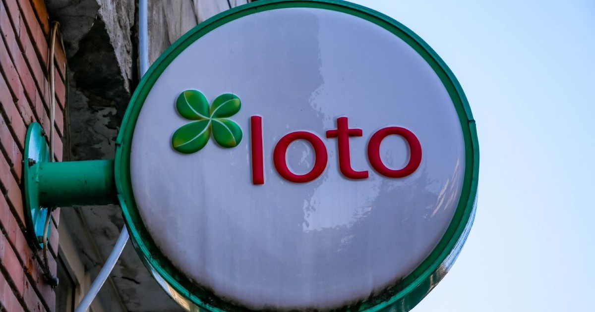Panou stradal pe care scrie Loto, afișat lângă o agenție a Loteriei Române, pe peretele unui bloc