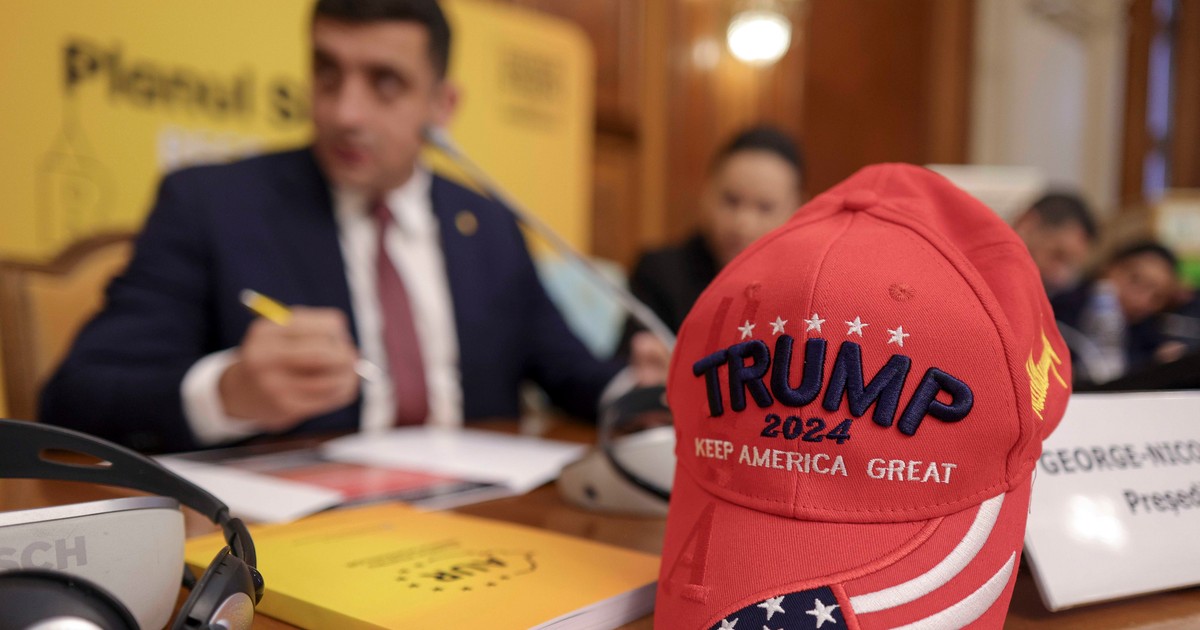 George Simion în fundal, o șapcă roșie cu Trump scris pe ea în prim plan.