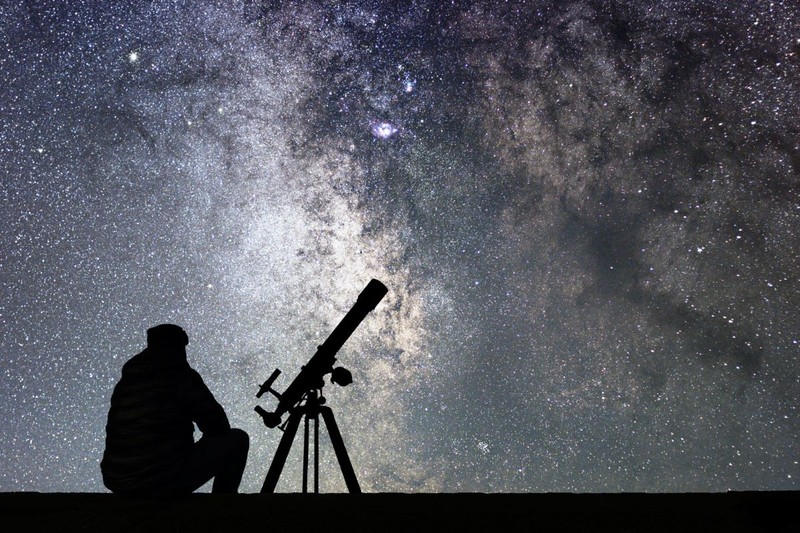 Man with astronomy telescope looking at the stars.