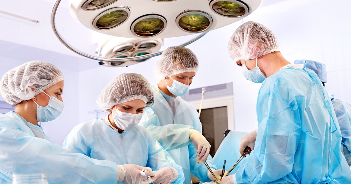 Mai mulți medici operează un pacient, într-o sală de operații