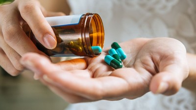 o femeie care toarnă pastilele în palmă dintr-o sticlă cu medicamente