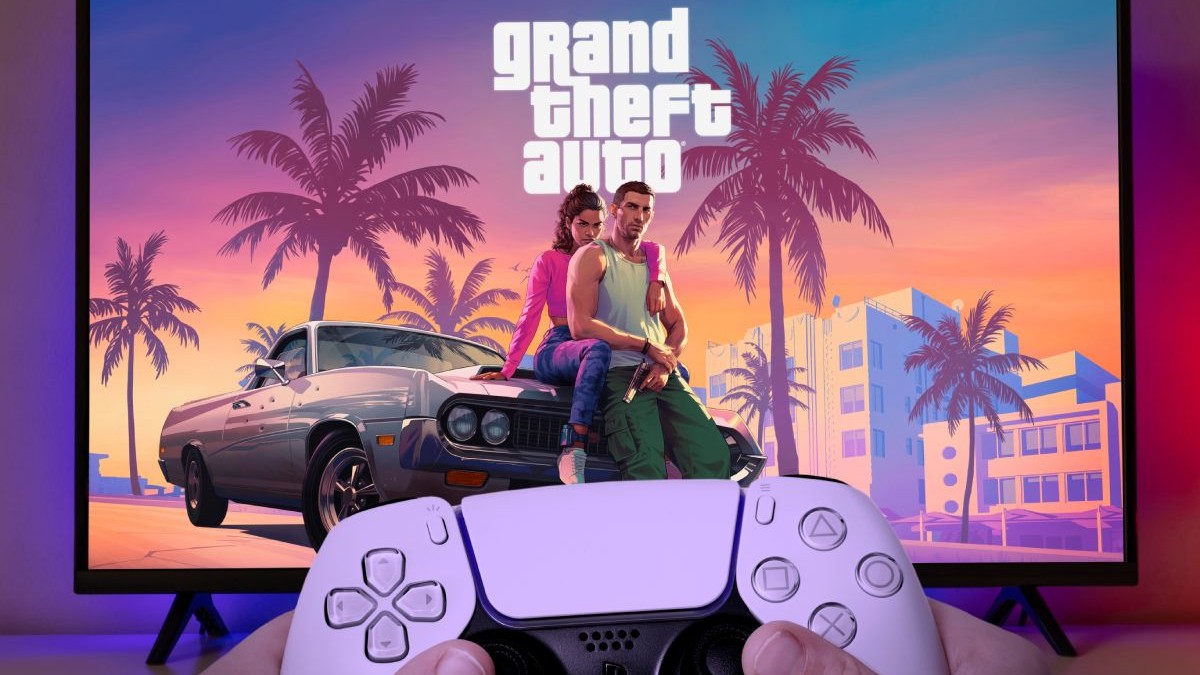 Un controller de Playstation ținut în fața unui televizor pe care se vede logo-ul GTA 6