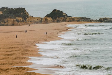 Oamenii se plimbă pe o plajă din Albufeira, sudul Portugaliei