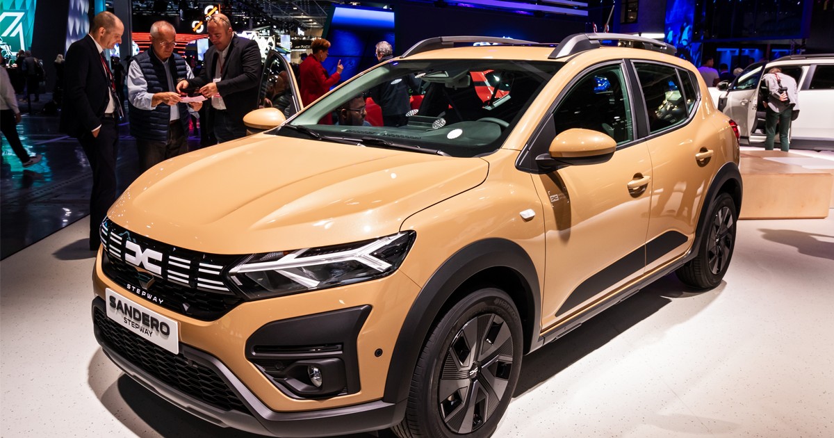 O Dacia Sandero la o expoziție de mașini este analizată de posibili clienți.
