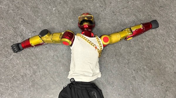 Un robot cu ochelari de soare, lanț de aur și mustață falsă, „reținut” de polițiști