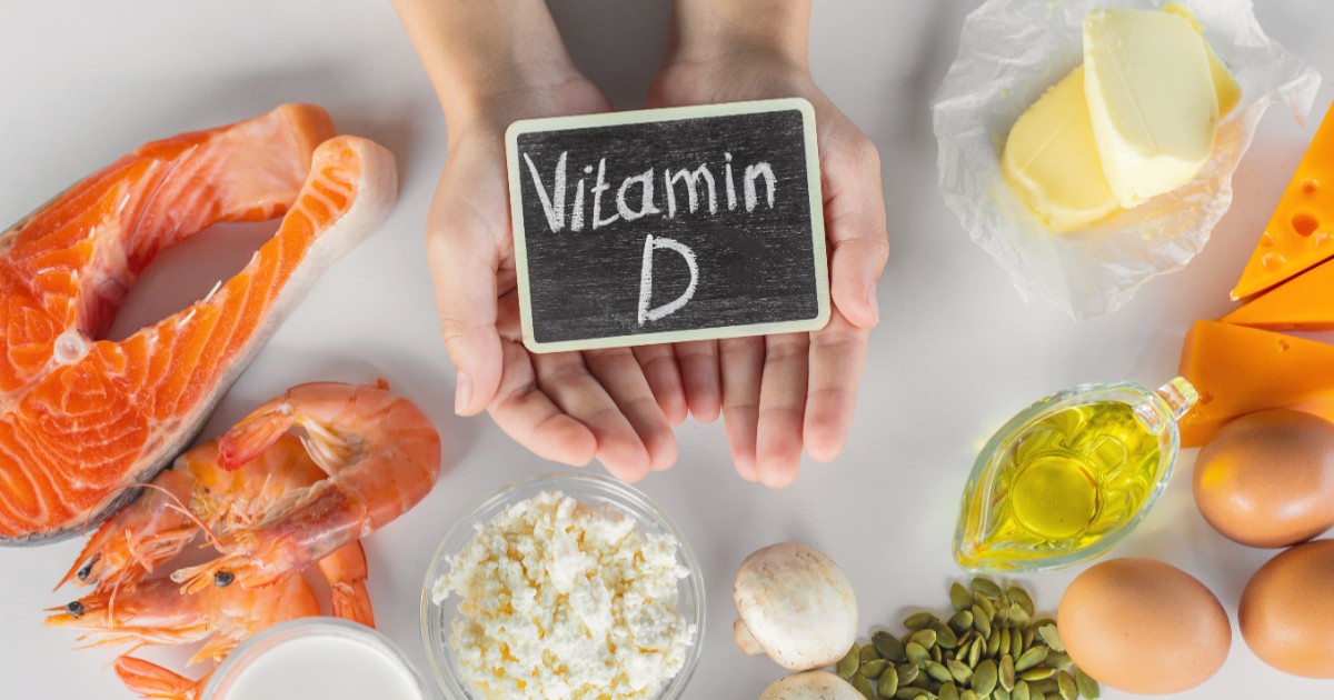 Imaginea prezintă o varietate de alimente bogate în vitamina D, incluzând somon, creveți, lactate (brânză de vaci, unt, lapte), ouă, ciuperci și semințe