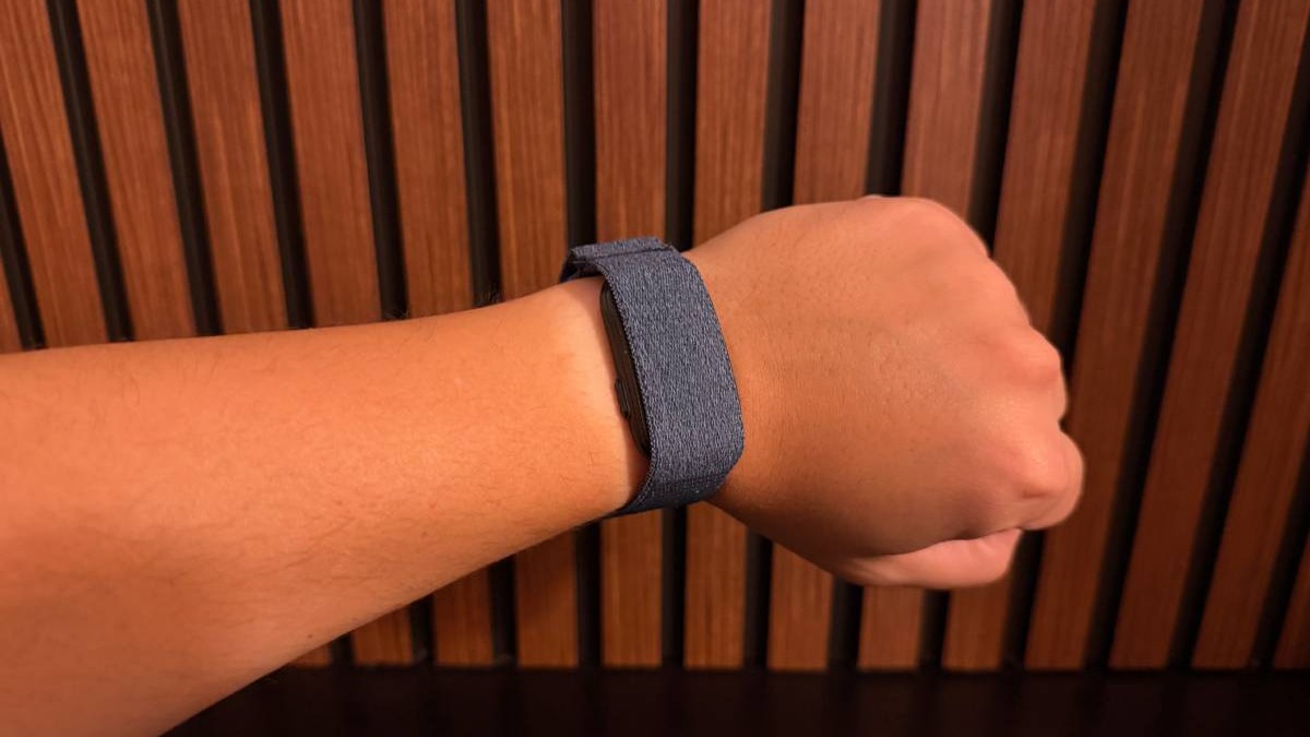 Garmin Cirqa, la încheietura unei mâini, în fața unui fundal de lemn.