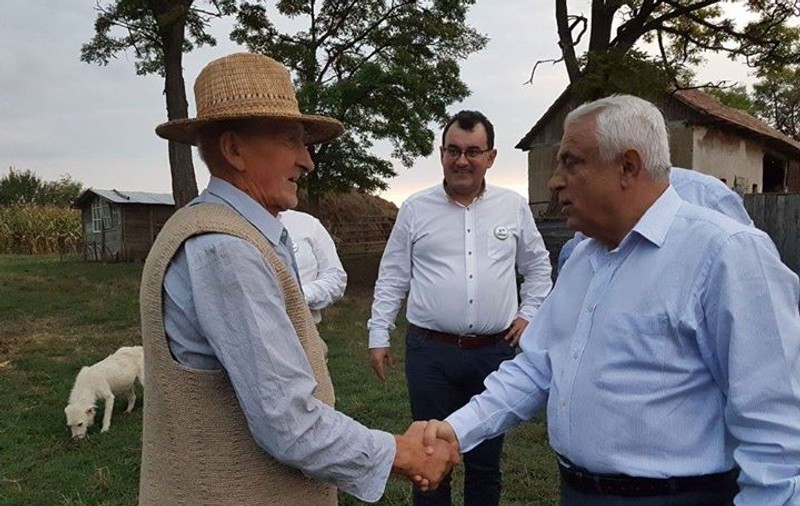 Petre Daea mănâncă jambon din portbagajul unei maşini. Ministrul laudă „savoarea şi gustul cărnii” de porc din rasa Bazna
