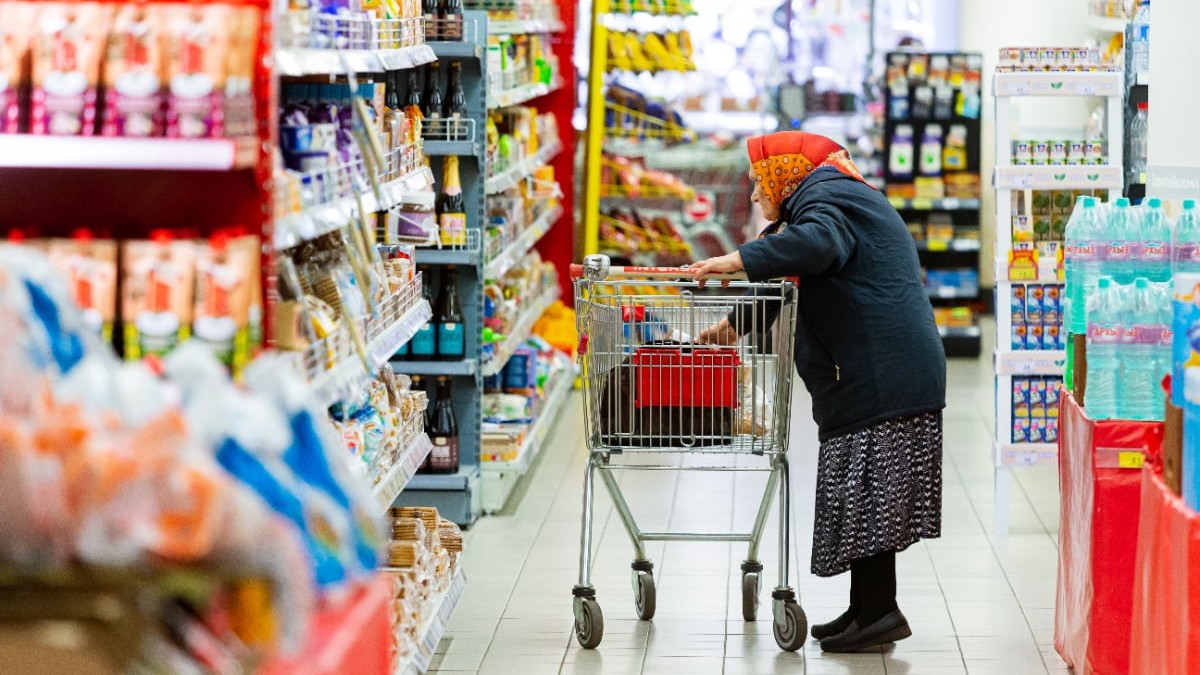 O femeie în vârstă, în timp ce stă cu un cărucior în supermarket