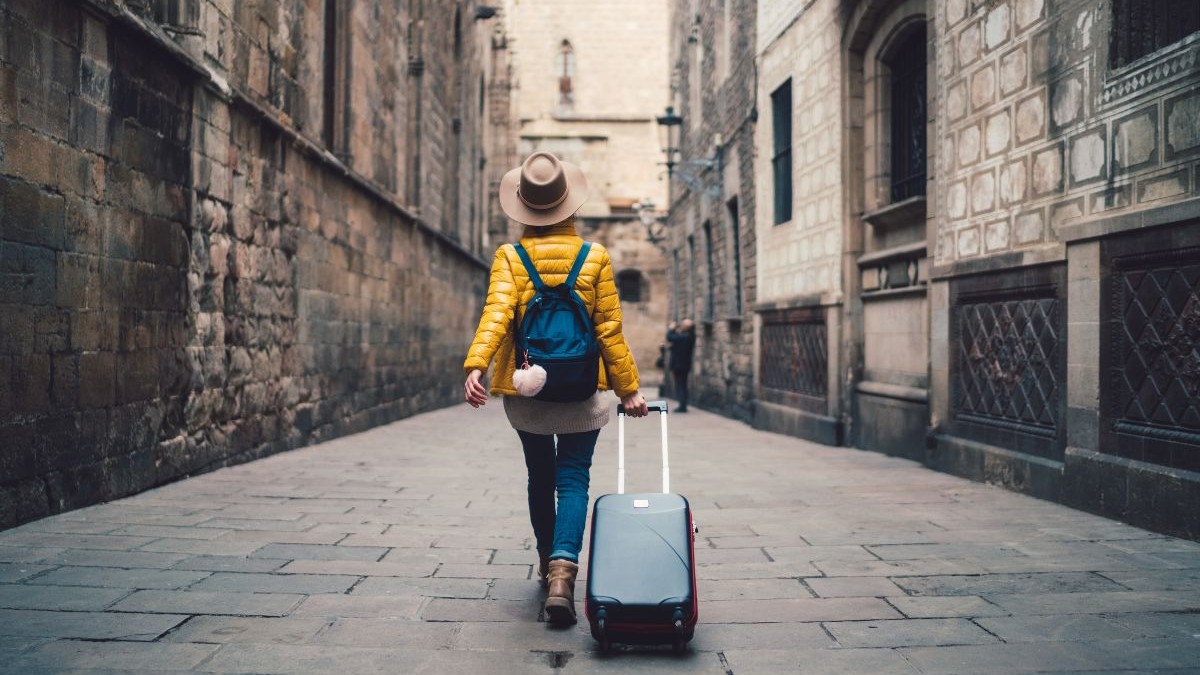 O tânără cu o valiză mergând pe stradă în Barcelona
