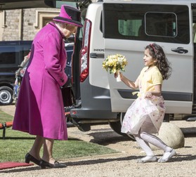 Dina Rayburn, în vârstă de șapte ani, îi dăruiește reginei Elisabeta a II-a flori în timpul unei ceremonii la castelul Windsor. Foto: Hepta