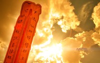 Un termometru ce indică o valoare ridicată de aproximativ 36 de grade Celsius, profilat pe un cer luminos de vară cu raze puternice de soare care creează un efect cald, portocaliu-auriu
