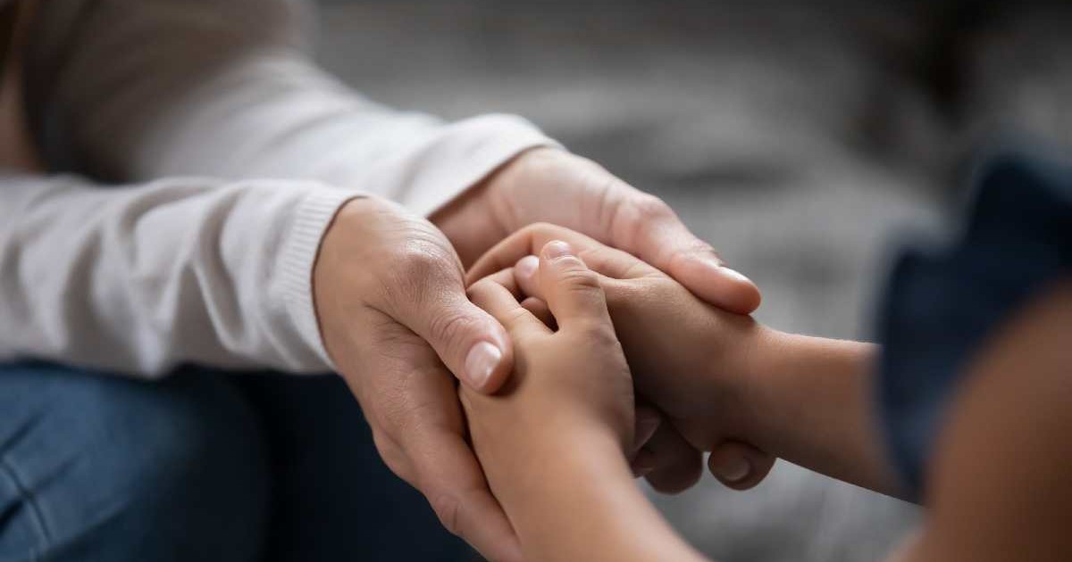 Prim-plan cu un tânăr părinte plin de compasiune care ține de mână o fetiță, sprijinind-o