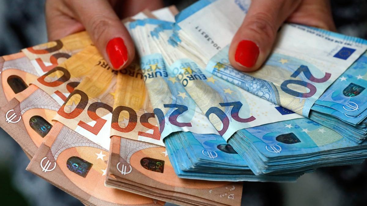 Femeie care ține bancnote și bancnote euro