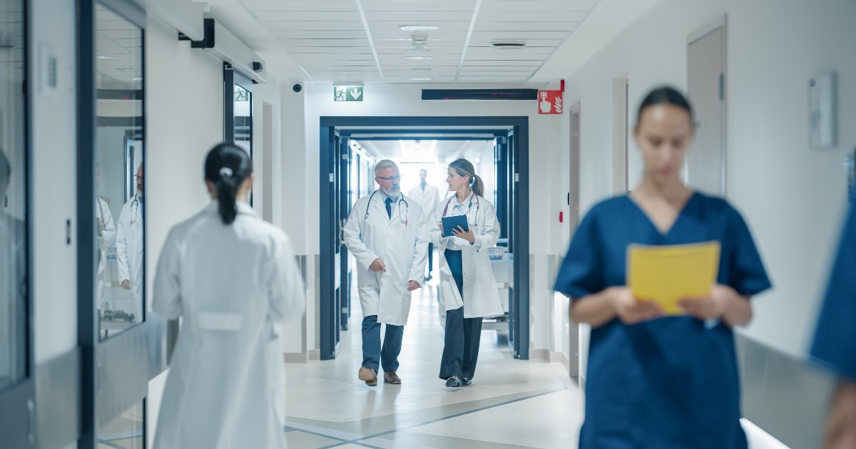 În imagine sunt ilustrați doctori și asistente, pe coridorul spitalului