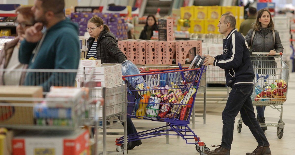 Persoane fac cumpărături într-un supermarket din București.