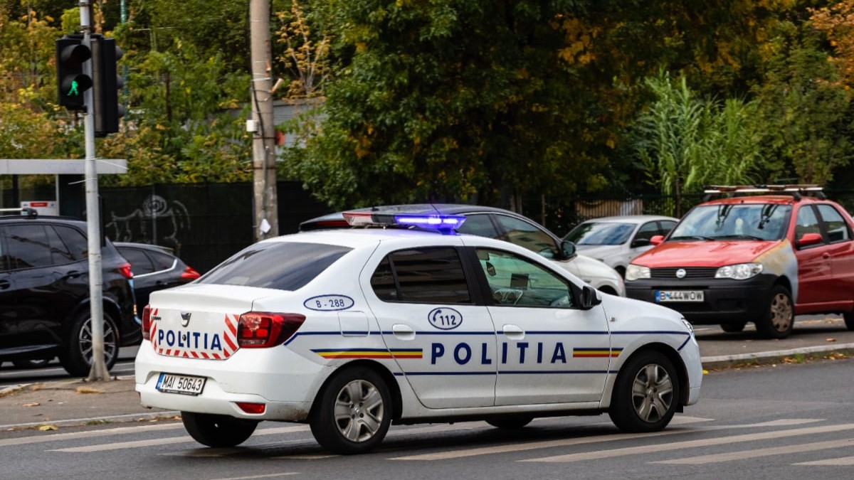 O mașină de poliție care circulă pe o stradă din România, are girofarurile aprinse