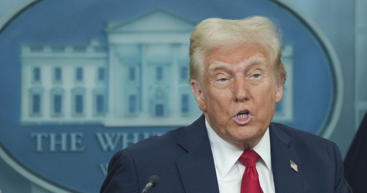 Donald Trump, îmbrăcat într-un costum albastru, cu cravată roșie, într-o conferință de presă la Casa Albă