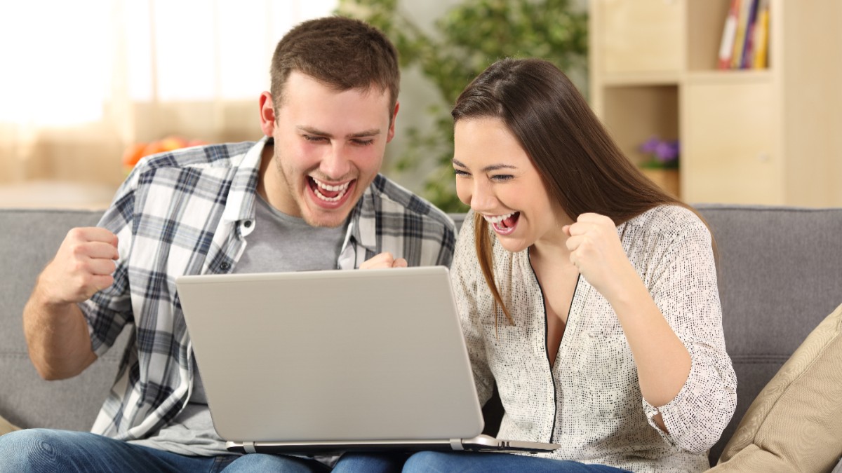 Un bărbat și o femeie bucuroși, în fața unui laptop.