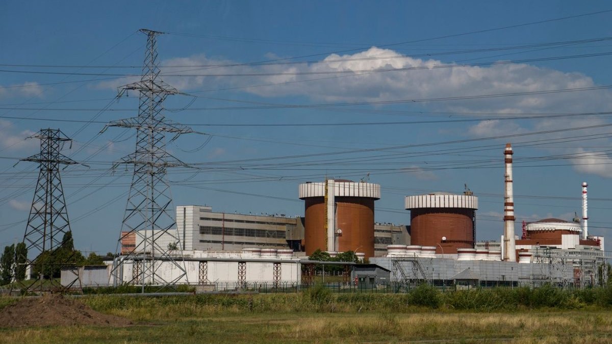 Centrala Nucleară Sud din Ucraina, văzuta de la depărtare, alături de mai mulți stâlpi de tensiune înalți și cu fire de curent legate deasupra