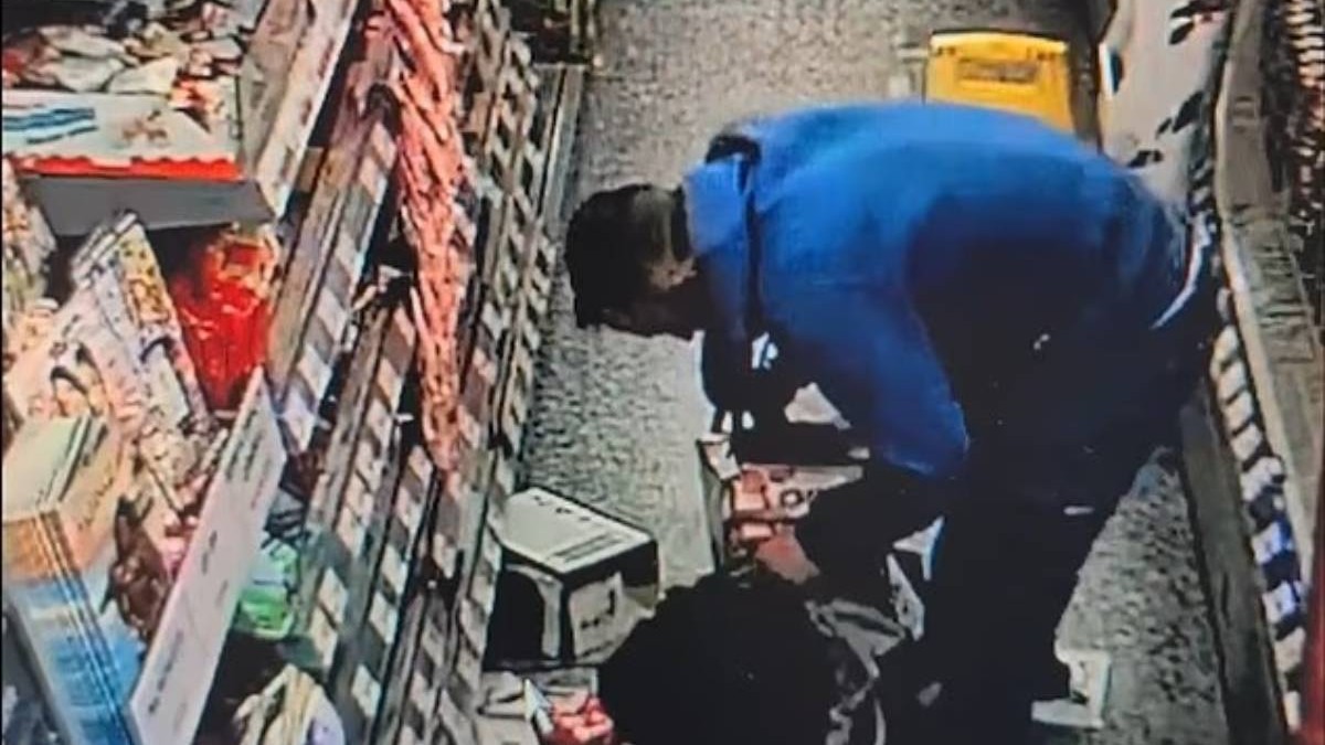 Un hoț de ciocolată din West Midlands, in hanorac albastru, stea aplecat peste o geanta in timp ce fura dulciuri de pe rafturile magazinelor, cutii de ciocolată.
