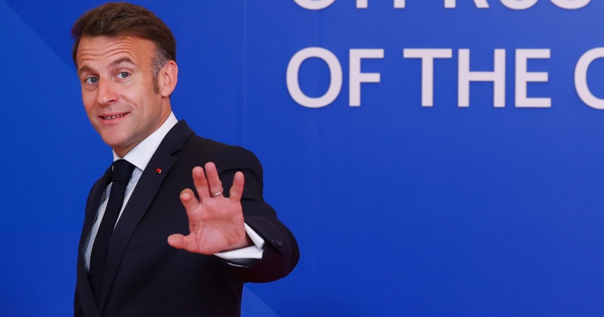 Emmanuel Macron îmbrăcat în costum, în Cipru, în timp ce se retrage de la conferința de presă și le face cu mâna jurnaliștilor
