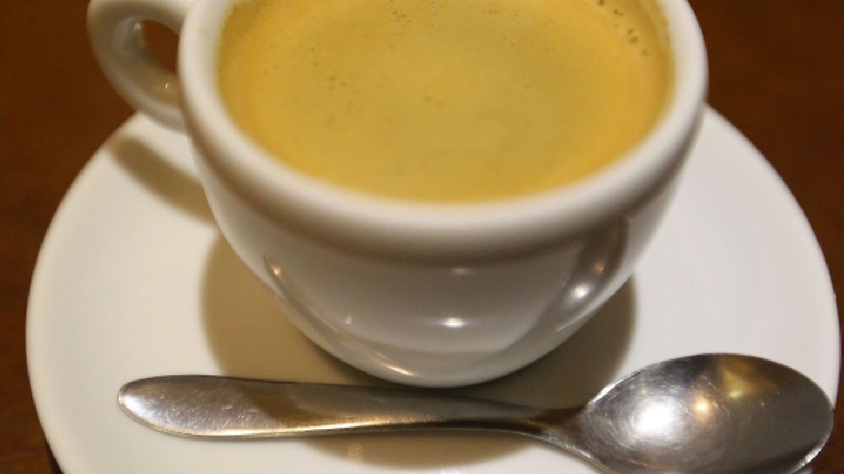 cească de cafea plină, pe o farfurioară, pe care se află și o linguriță