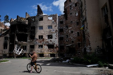 Un bărbat pe bicicletă face fotografii cu clădiri avariate, distruse de atacurile din Irpin, la periferia orașului Kiev, Ucraina, joi, 26 mai 2022. Foto: Profimedia