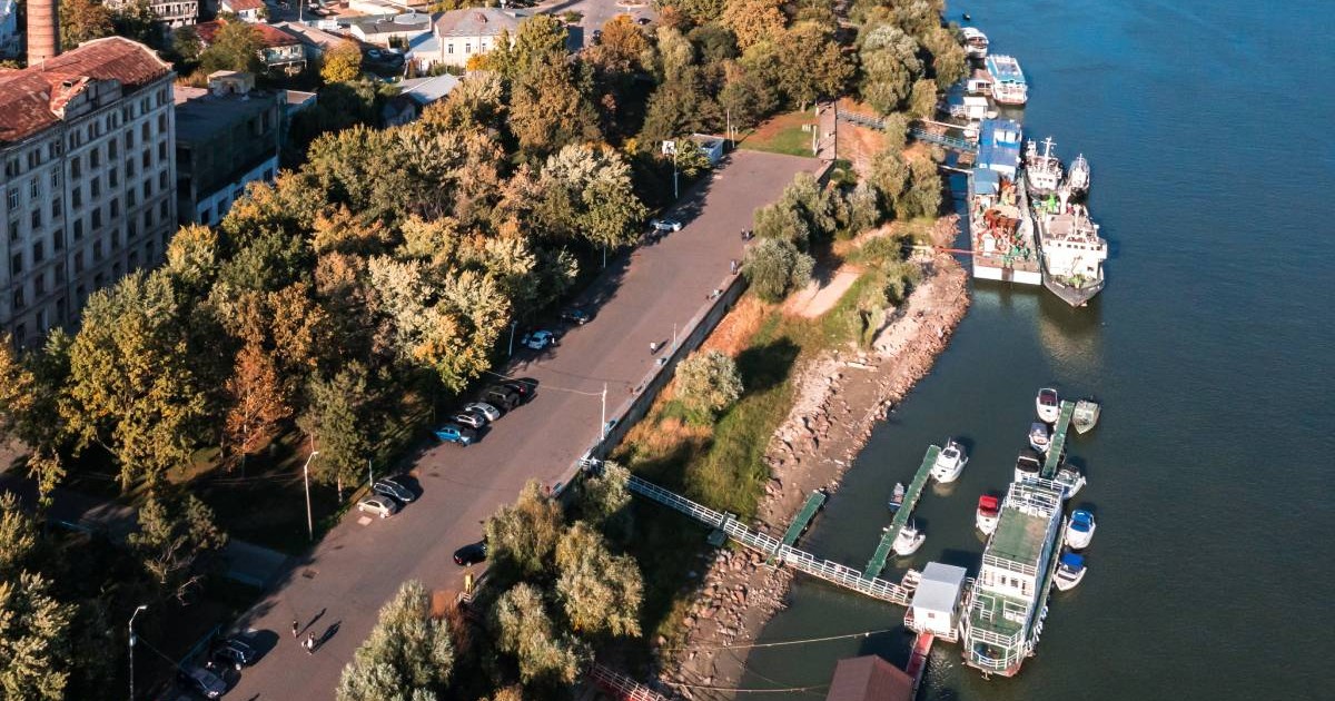 Vedere aeriana a orașului Brăila in zona navala, mai multe ambarcatiuni pe Dunăre, se vede si o șosea in stanga, copaci, toamna