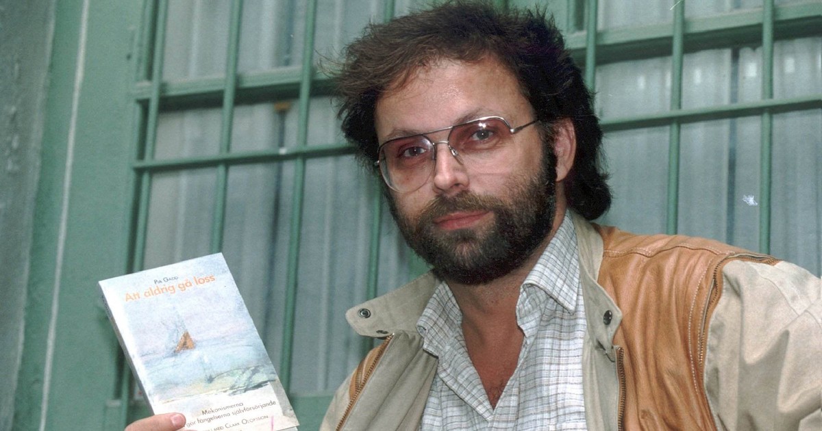 Imagine cu Clark Olofsson ținând în mână o carte. Infractorul poartă ochelari, o cămașă albă cu dungi și o jachetă maro. Fotografia a fost făcută în toamna anului 1991