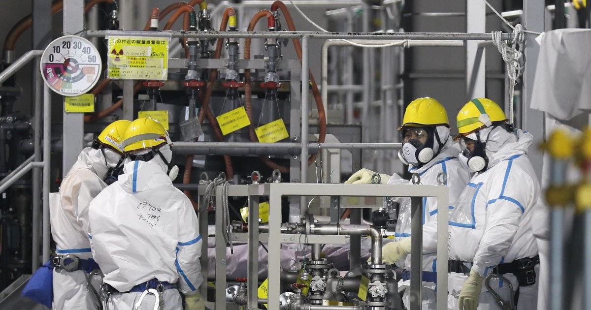 Muncitori îmbrăcați în combinezoane și purând măști verifică sistemul de procesare a apei ALPS, care procesează apa contaminată pentru a o stoca în rezervoarele de la centrala nucleară Fukushima, ianuarie 2020