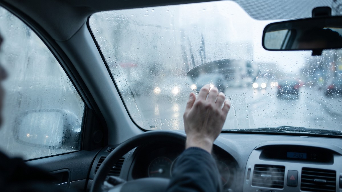Un șofer care șterge parbrizul mașinii, aburit