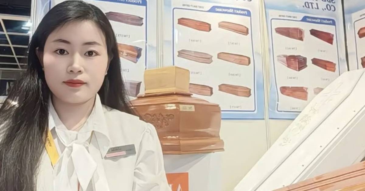 Lisa Liu, o tânîră fostă profesoară Heze, China, cu padrul desfăcut si o bluza albă, la un stand de prezentare sicrie. in spate se vad mai multe modele din lemn de paulownia