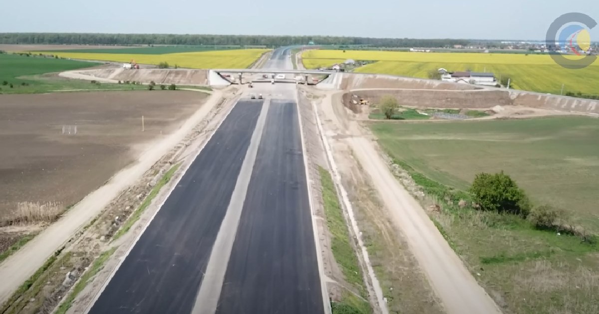 Santier autostrada, pasaj nefinalizat, fotografiat de sus, în stânga/dreapta marginit de câmpuri galbene de rapiță