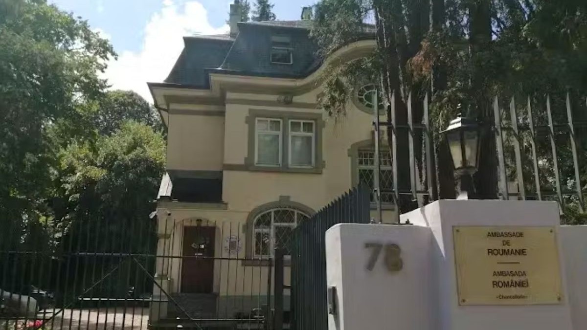 Clădirea în care are sediul Ambasada României la Berna, Elveția, cu vegetație pe fundal, într-o clădire cu etaj de culoare galbenă