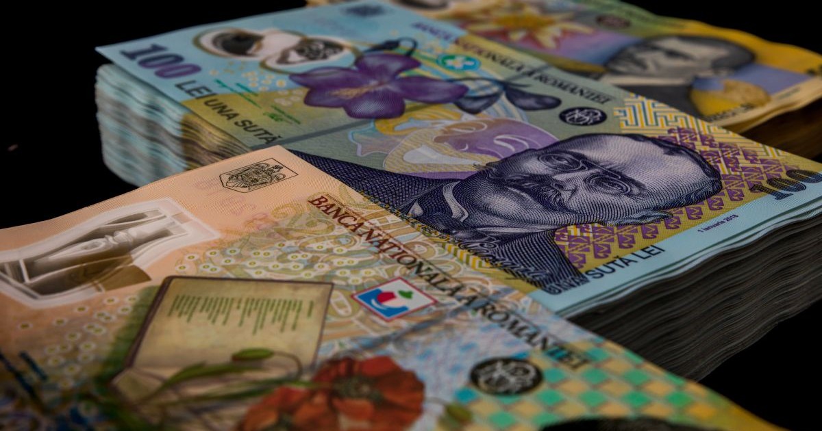 Trei teancuri de bani în bancnote de lei românești din cupiura de 50, 100 și 200 de lei, pe fundal negru