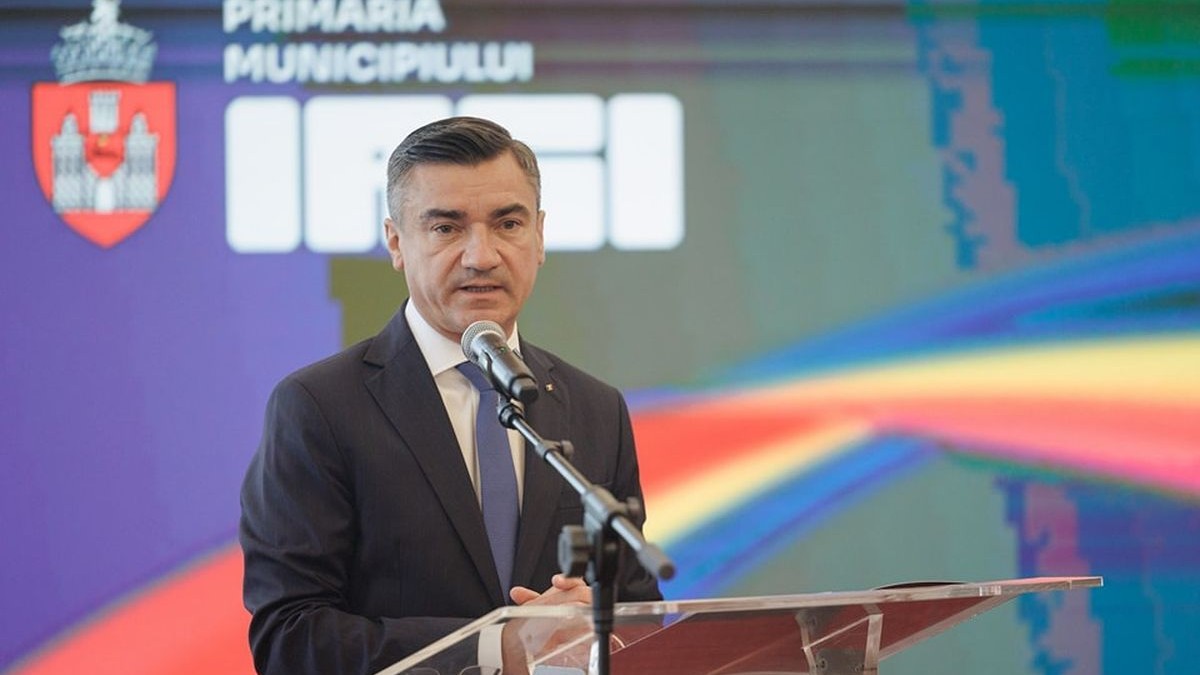 Mihai Chirica vorbește de la un pupitru, având în spate sigla municipiului Iași