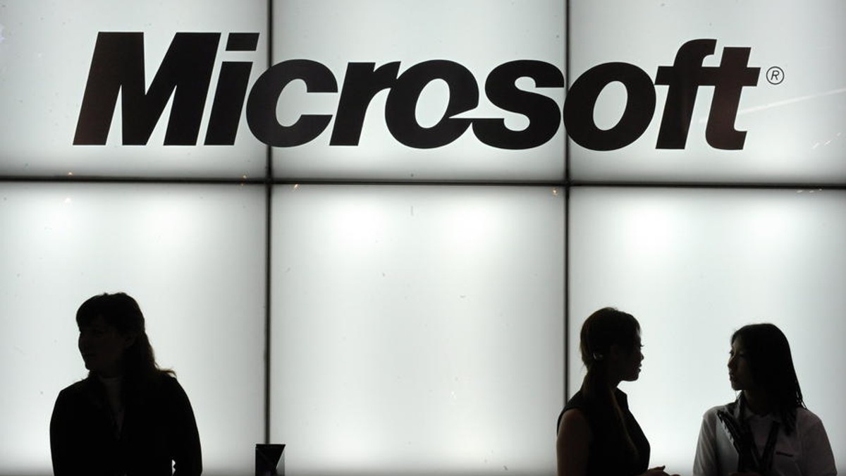 După Apple, a venit rândul Microsoft să avertizeze asupra efectelor epidemiei de coronavirus: gigantul american a anunțat că vânzările pentru sistemul de operare Windows și divizia sa de PC-uri nu se vor ridica la nivelul anterior. Logo Microsoft luminat, cu trei siluete de oameni în față