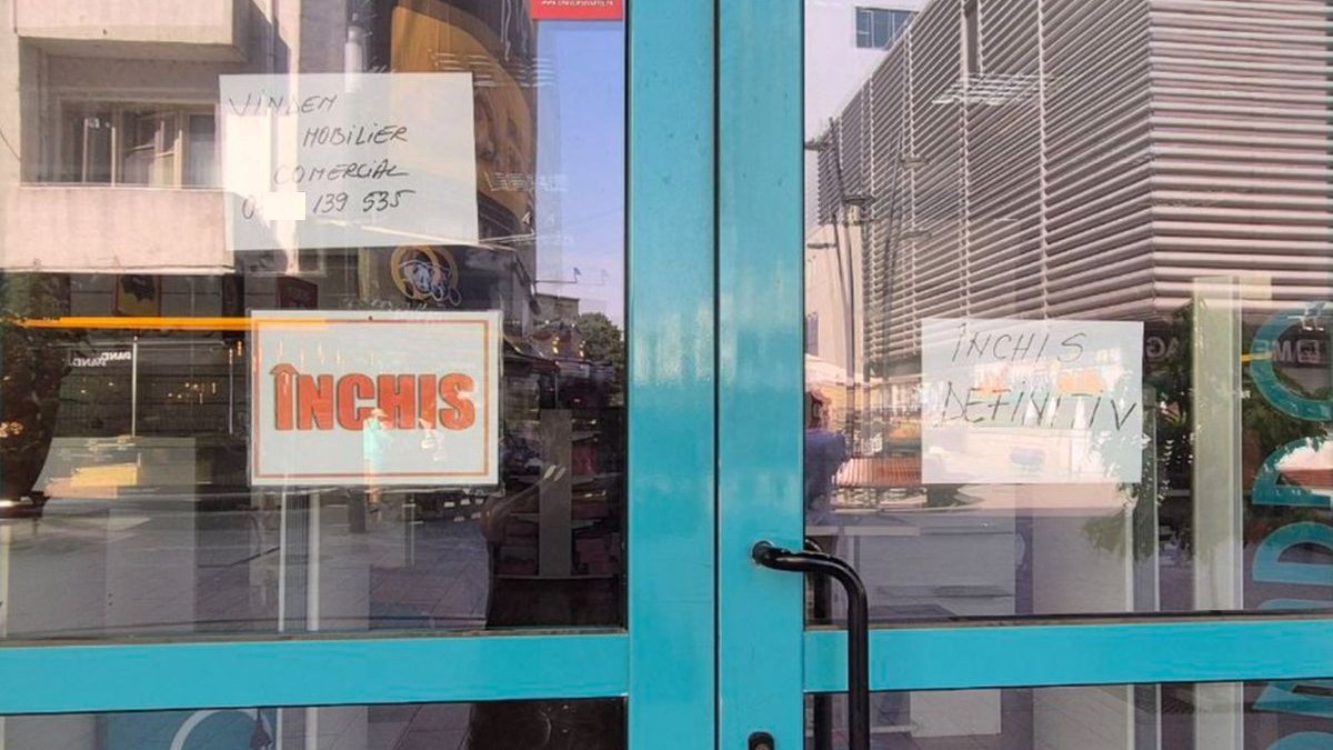 Ușile închise ale unui magazin, pe care scrie Închis definitiv, iar un anunț pus pe geam arată că se vinde mobilierul comercial, în Constanța, iulie 2025