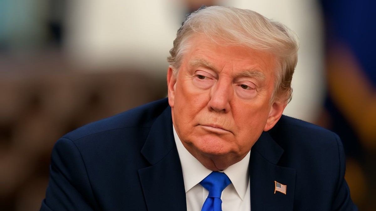 Donald Trump, în prim plan, îmbrăcat într-un costum negru, cu cămașă albă și cravată albastră, pe fundal blurat