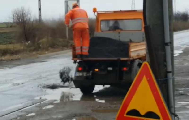 Drumarii asfaltează gropile pline cu apă în Dolj. Bălțile, umplute cu criblură încinsă / VIDEO