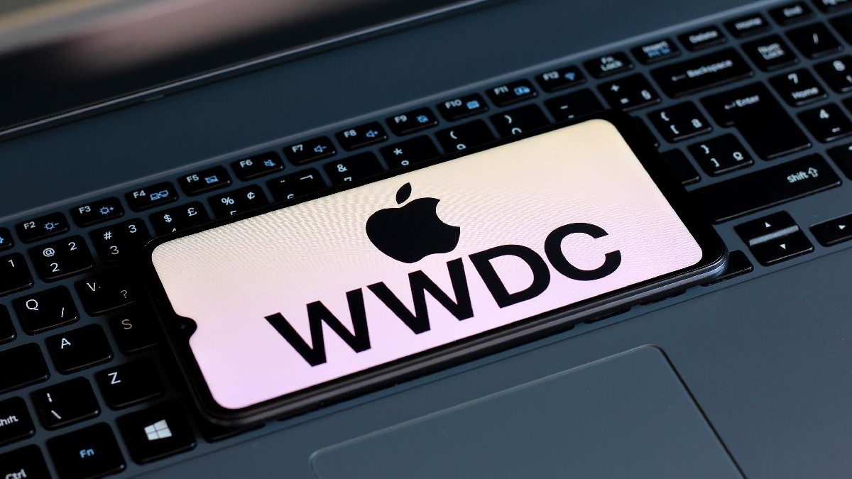 Logoul Apple WWDC, pe un ecran al unui smartphone așezat pe o tastatură de laptop.