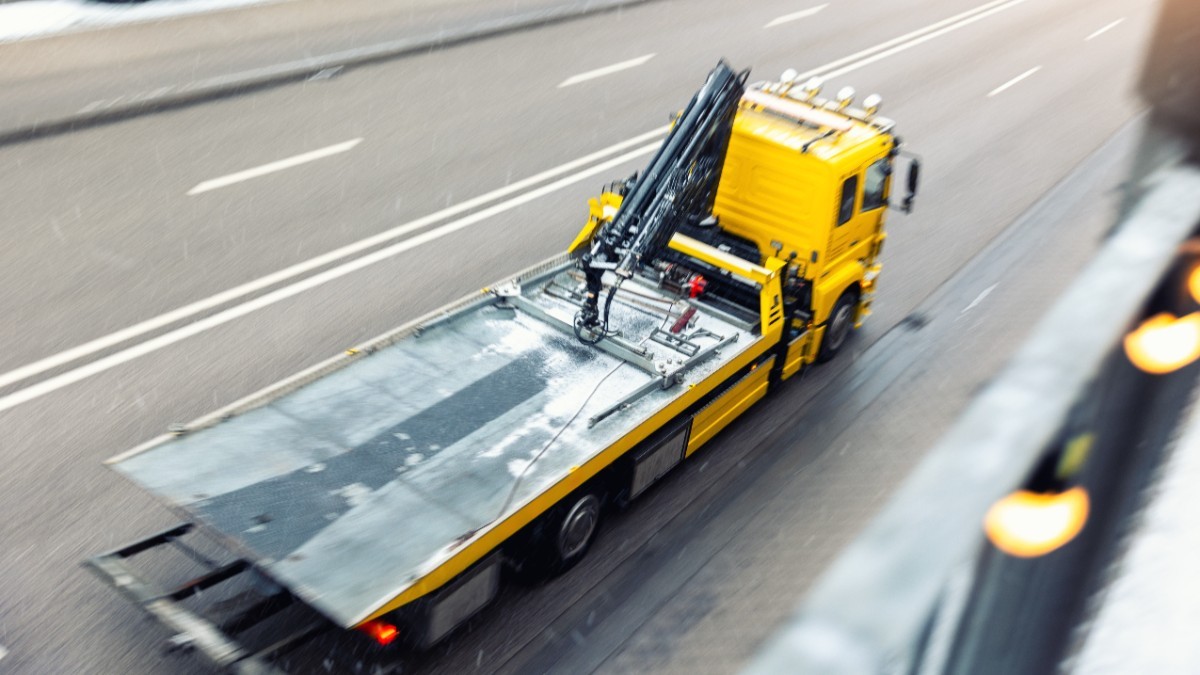 Un camion cu platformă pentru tractare, în timp ce circulă pe șosea