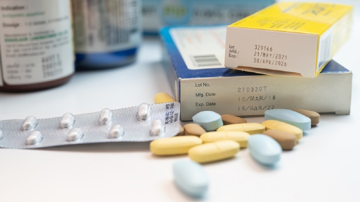 Mai multe cutii si borcane cu medicamente expirate asezate pe o masa alba