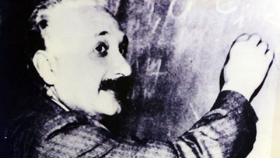 Imagine alb-negru cu Albert Einstein, in timp ce scrie pe o tablă