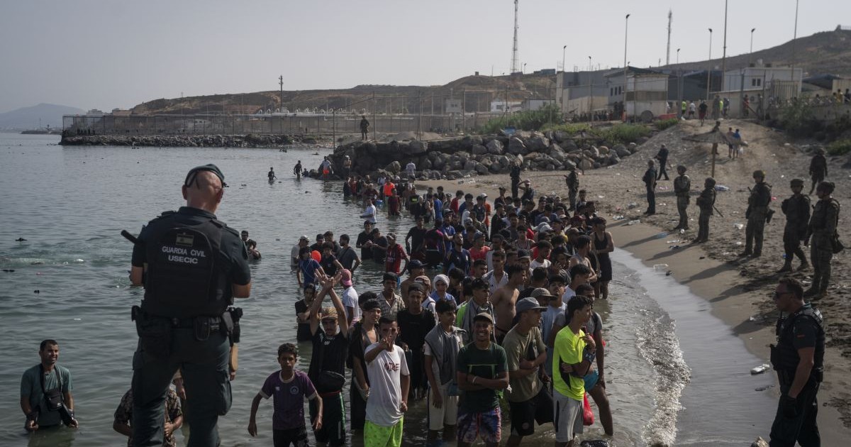 Membri ai unității USECIC din cadrul Gărzii Civile (Guardia Civil) supraveghează migranți pe plaja Tarajal, după ce aceștia au trecut frontiera dintre Spania și Maroc, la 31 iulie 2026, în Ceuta, Spania